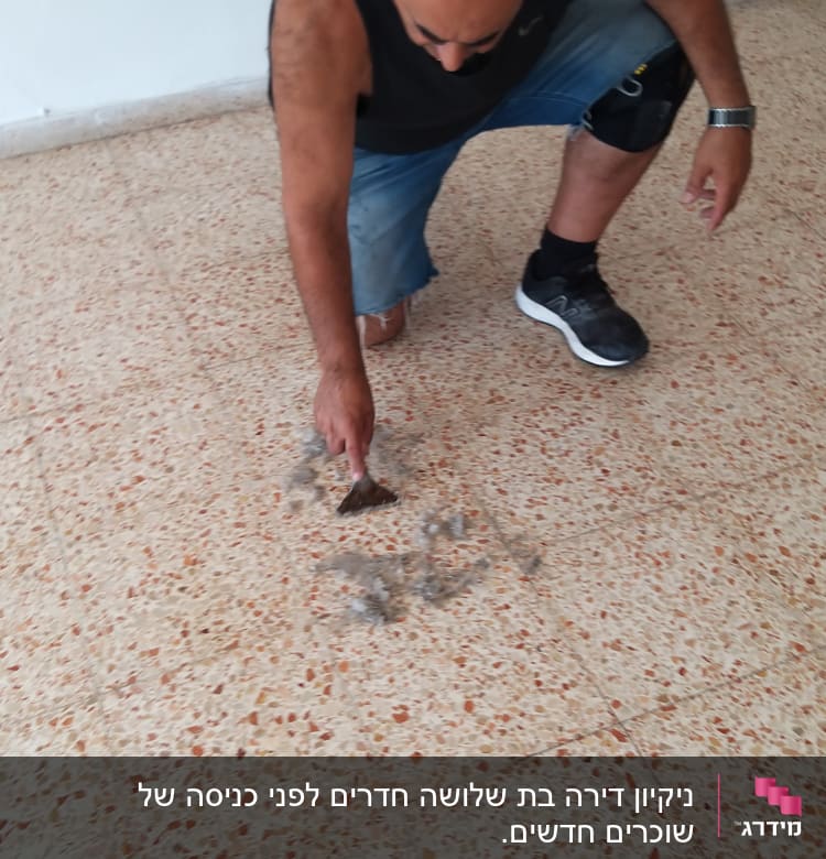 אדם מנקה רצפה עם מגרפה קטנה